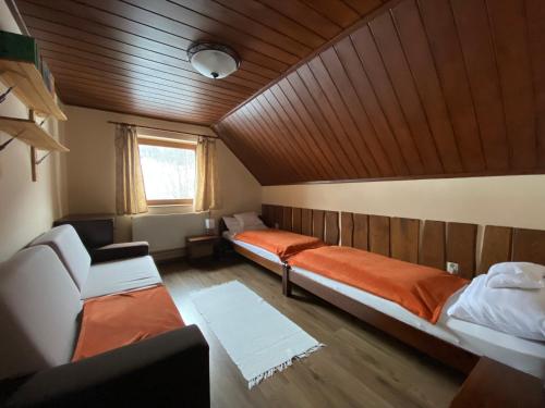 マートラゼンティムレにあるBelle-Aire Vendégház Mátraszentlászlóのベッド2台、ソファ、窓が備わる客室です。