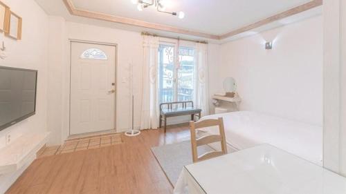 a living room with a television and a table and chair at Tinkerbell Pension in Gyeongju