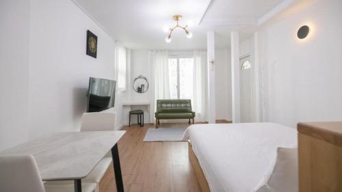 a white bedroom with a bed and a chair at Tinkerbell Pension in Gyeongju