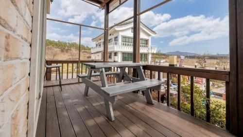 a wooden deck with a picnic bench on a balcony at Tinkerbell Pension in Gyeongju
