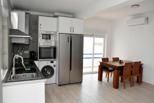 a kitchen with a stainless steel refrigerator and a table at Casa Azul in Monte Gordo