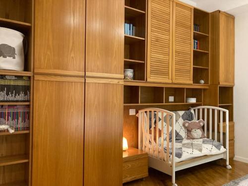 a baby crib in a room with wooden shelves at Thesan Lodge, chic & modern design apartment in Grosseto