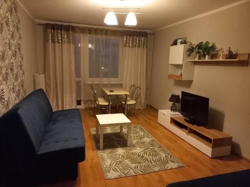 a living room with a blue couch and a table at Apartament M-3 in Częstochowa