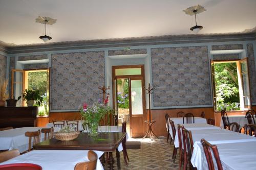 un comedor con mesas y sillas blancas y ventanas en Beau Séjour, en Bocognano