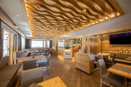 um restaurante com tectos e mesas e cadeiras de madeira em Albergo Garnì Antico Mas del Medico em Cavalese