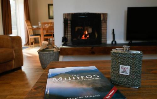 a book sitting on a table in a living room with a fireplace at Cologin Farmhouse in Oban