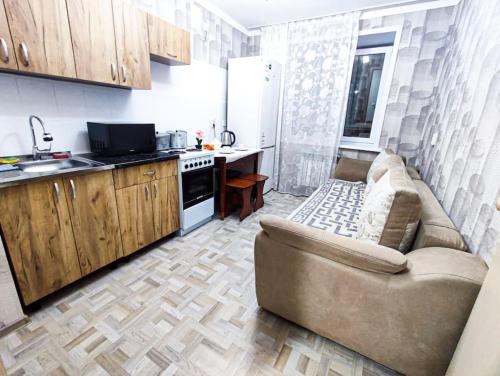 sala de estar con sofá y cocina en Уютные апартаменты прям в центре города, en Pavlodar