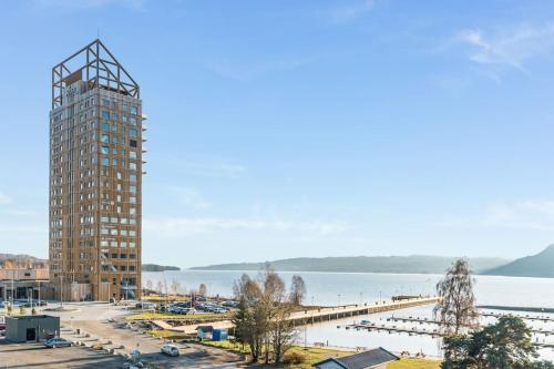 un edificio alto junto a un gran cuerpo de agua en MJOS TOWER Suite - Lovely lake view, en Brumunddalen