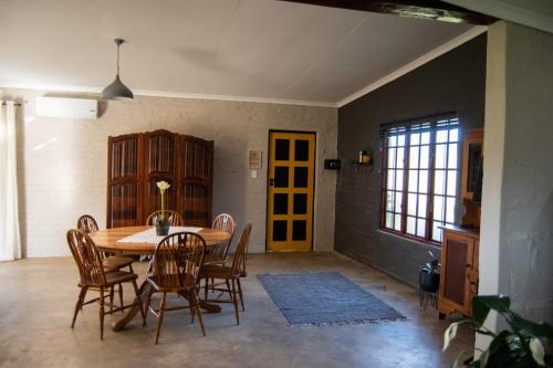 The Mustard Seed Guesthouse في بلومفونتين: غرفة طعام مع طاولة وكراسي خشبية