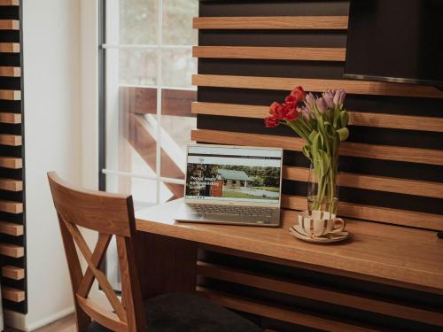a laptop computer sitting on a desk with a vase of flowers at Pasieka Podlaska Tradycja in Siemiatycze