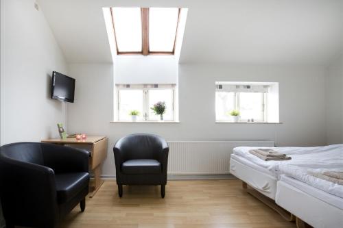 a bedroom with a bed and a chair and two windows at Motel Stege in Stege