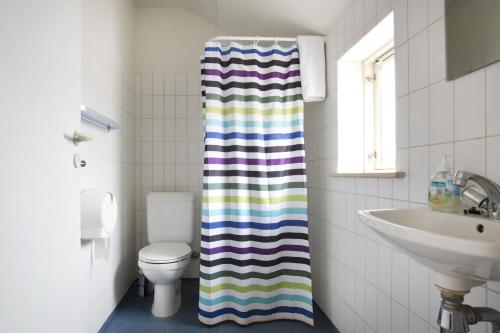 ein Badezimmer mit einem WC und einem gestreiften Duschvorhang in der Unterkunft Motel Stege in Stege
