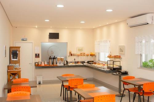 kuchnia z pomarańczowymi krzesłami i stołami w pokoju w obiekcie Hotel e Pousada Bem Bom - Itu w mieście Itu