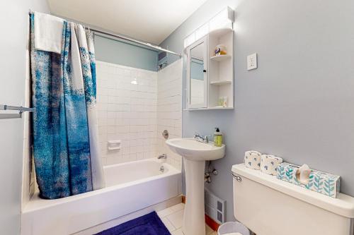 a bathroom with a blue shower curtain and a sink at Lakeside Delight, unit 423 in Laconia