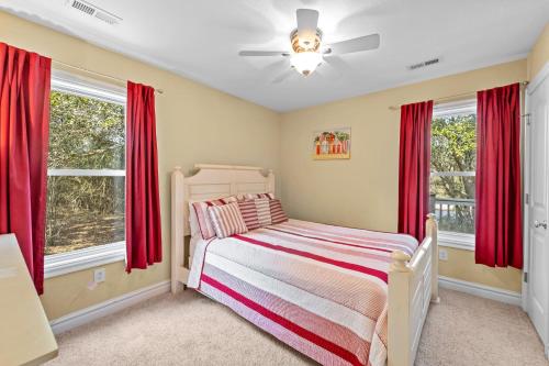 Southern Shores的住宿－The Sandlot，一间卧室配有床和两个带红色窗帘的窗户。