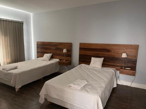 Habitación de hotel con 2 camas con sábanas blancas en La Americana, casa entre sierras en Luján