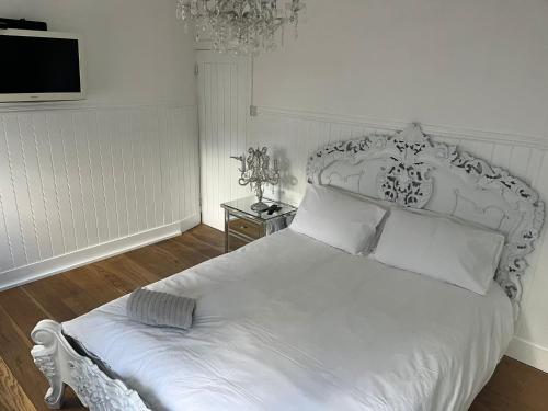 een slaapkamer met een wit bed en een tv aan de muur bij Beautiful Little Bungalow, Indoor Fireplace, & Bar in Ash
