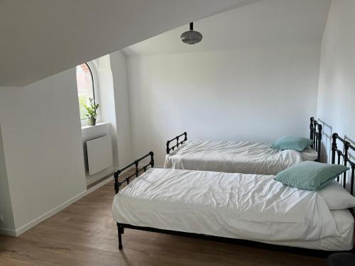 two beds in a white room with a window at Modern country house near Fontainebleau in Samoreau