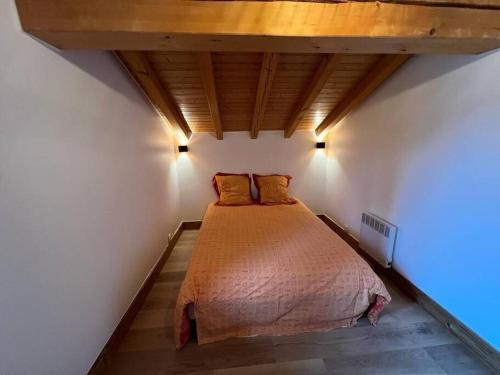 a bed in a bedroom with a wooden ceiling at Appart Duplex Chalet plein Sud in Feissons-sur-Salins