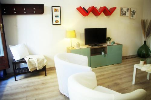 een woonkamer met witte stoelen en een televisie bij QuickHome La Ninfea in Viverone