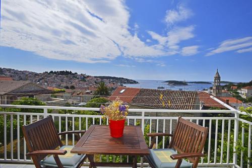 a table with two chairs and a vase of flowers on a balcony at Apartments and Rooms Bonkan Hvar in Hvar