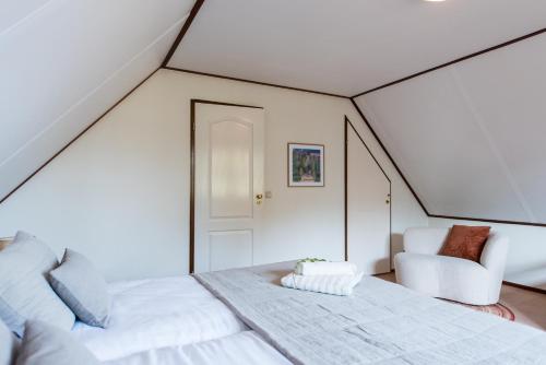 a attic bedroom with two beds and a chair at Villa met grote tuin in de duinen nabij het strand in Buren
