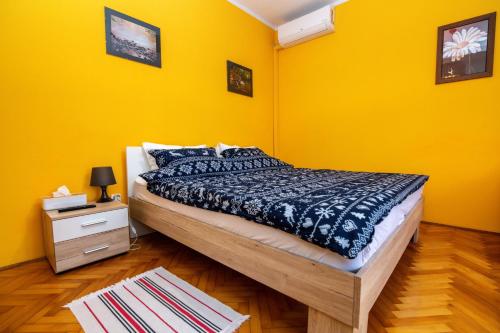 a bedroom with a bed and a yellow wall at Apartments Kinkela in Opatija