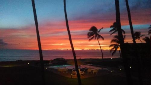 a sunset over the ocean with palm trees in the foreground at ***SERENDIPITY ON THE MOANA - Legal & Oceanfront - Great for Work & Play!*** in Waianae
