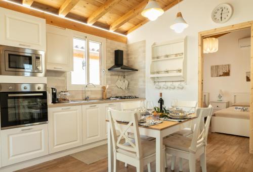 a kitchen with white cabinets and a table with chairs at Case Vacanze la fenice- Casa Mediterranea in Cava dʼAliga