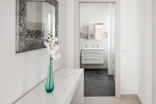 een witte badkamer met een vaas met bloemen op een toonbank bij Civico40 Luminoso appartamento con balconi e garage privato in Verona