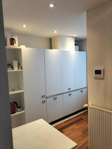 eine Küche mit weißen Schränken in einem Zimmer in der Unterkunft Appartement - Quartier européen in Brüssel