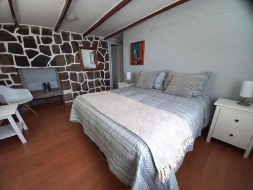 um quarto com uma cama grande e uma parede de pedra em Lodge Andes em Farellones