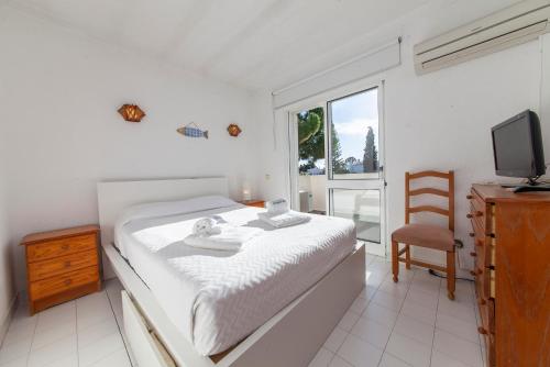 een slaapkamer met een bed, een televisie en een stoel bij B75 - Casa Delfim in Alfanzina Carvoeiro in Poço Partido