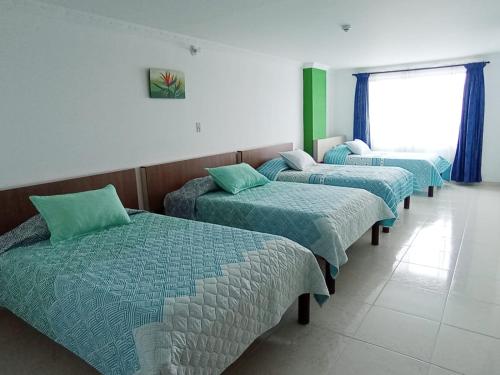 a row of beds in a room with a window at Diamante Blue Hotel in Villavicencio