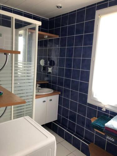une salle de bain carrelée bleue avec un lavabo et une baignoire dans l'établissement Bel appartement 60m2 vue mer La Baule Escoublac, à La Baule