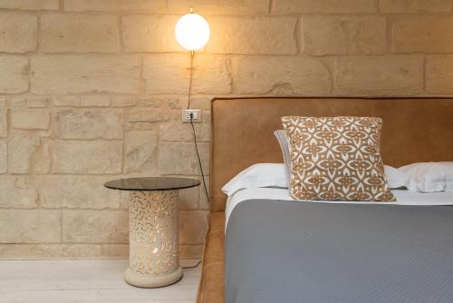 a bedroom with a bed with a table and a brick wall at Le Nicchie luxury rooms in Lecce