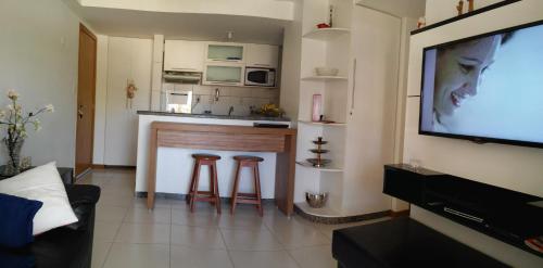 een woonkamer met een televisie en een keuken bij Paraíso dos Corais in Guarajuba