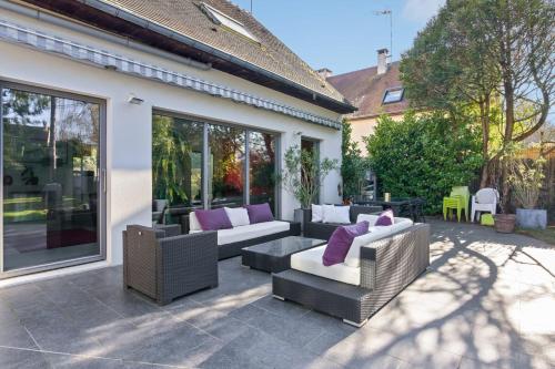 eine Terrasse mit 2 Sofas und einem Tisch mit lila Kissen in der Unterkunft Villa des Puits - Welkeys in La Celle-Saint-Cloud