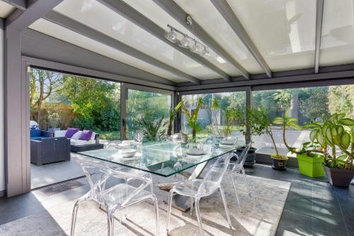 ein offenes Wohnzimmer mit einem Glastisch und Stühlen in der Unterkunft Villa des Puits - Welkeys in La Celle-Saint-Cloud