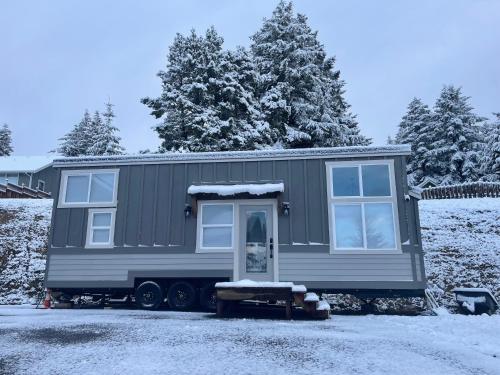 una casita verde estacionada en la nieve en Delightful Tiny Home w/ 2 beds and indoor fireplace, en McKinleyville
