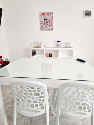 a white table and two white chairs in a room at Dpto Live in Caleta Olivia