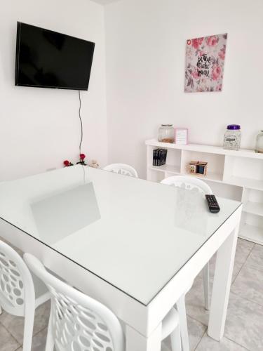 una mesa y sillas blancas con TV en la pared en Dpto Live en Caleta Olivia