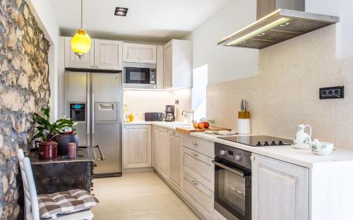 a kitchen with white cabinets and stainless steel appliances at villa Storia in Dobrinj