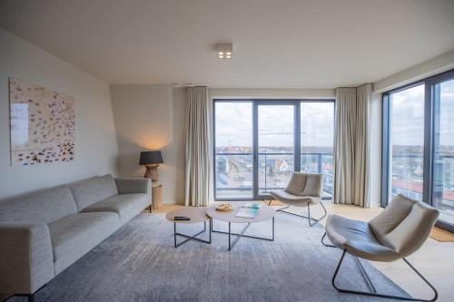 a living room with a couch and chairs and windows at Georgie Light, lofty luxurious in Cadzand