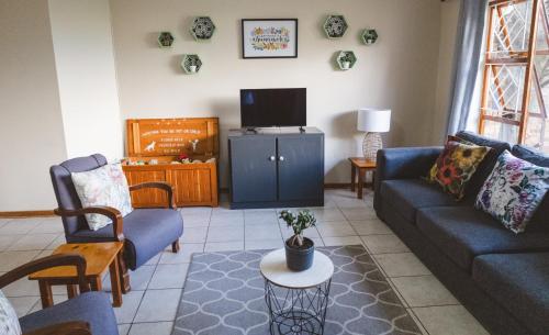 a living room with a couch and a tv at Habitat Place in Bloemfontein