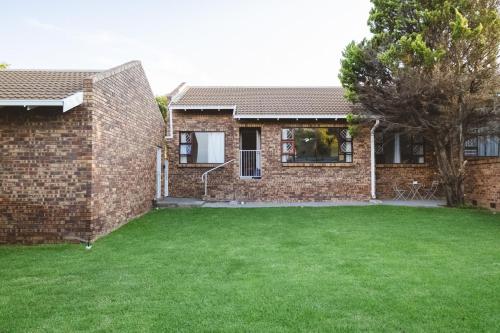 una casa de ladrillo con un césped verde delante de ella en Habitat Place, en Bloemfontein