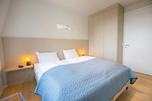 um quarto com uma cama grande e um cobertor azul em Georgie Light, lofty luxurious em Cadzand