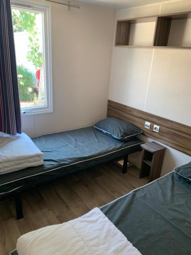 Cette chambre comprend 2 lits et une fenêtre. dans l'établissement Mobilhome 5 VO32, à Vias