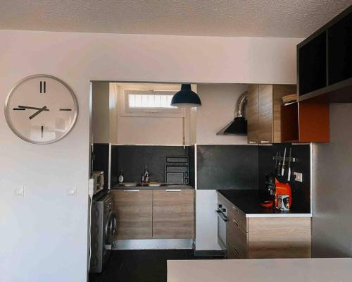 eine Küche mit einer großen Uhr an der Wand in der Unterkunft Appartement coconing , parking privé, climatisation & WIFI in Montpellier