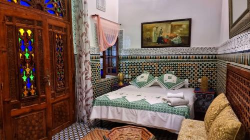 a bedroom with a bed and a stained glass window at Dar La Bague de Kenza in Fez